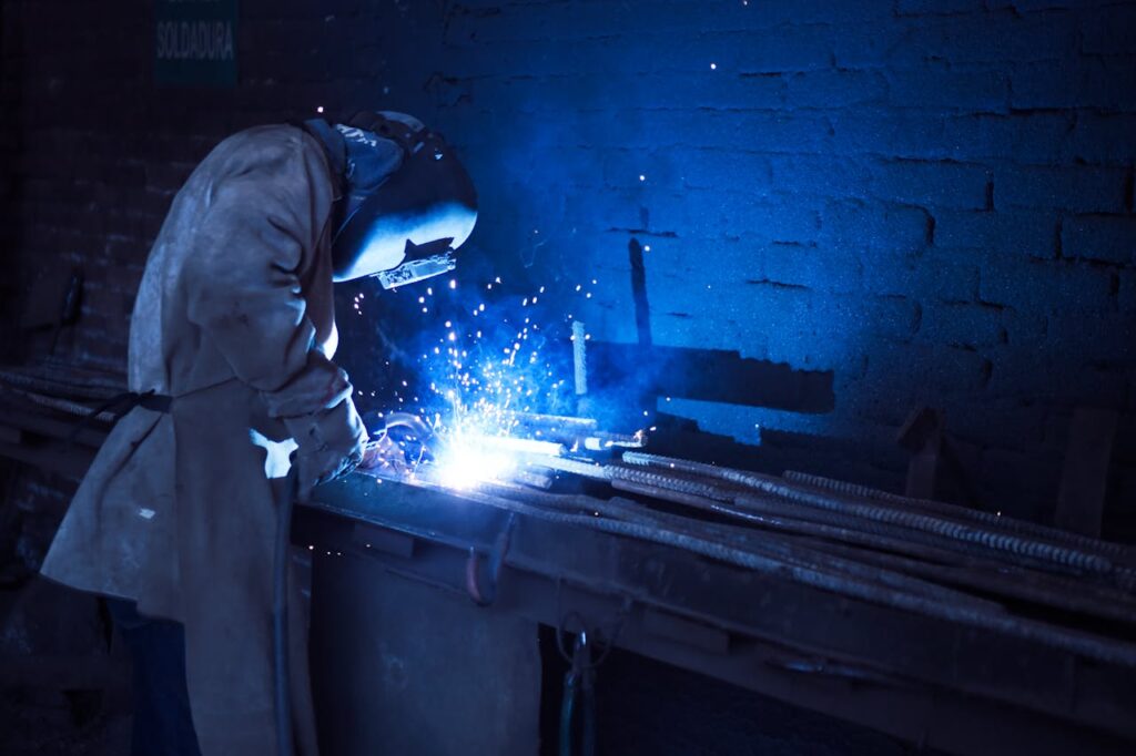 pexels-photo-1474993 Man Wearing Welding Helmet Welding Metal Near Gray Brick Wall