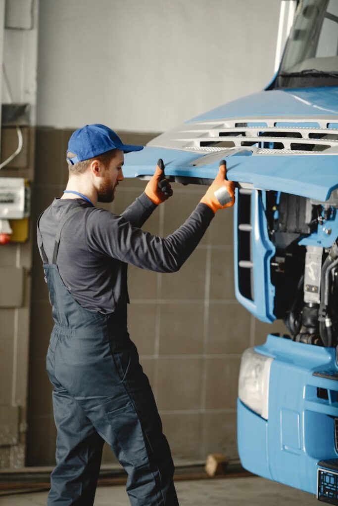 pexels-photo-6720536 Man in Work Clothes and Blue Cap Opening Front Mask of Blue Truck